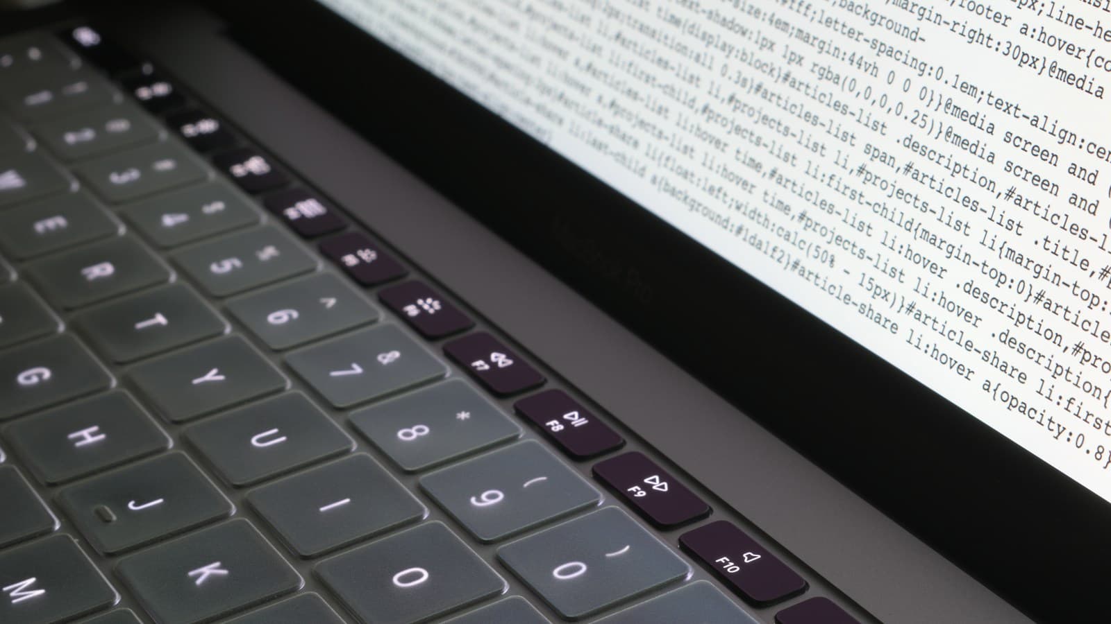 Ein geöffneter Laptop mit Programmcode in einer dunklen Arbeitsumgebung