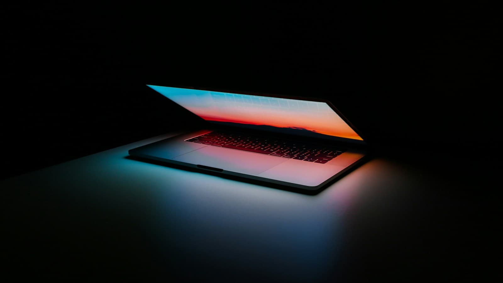 Notebook na tmavom stole s osvetlenou obrazovkou